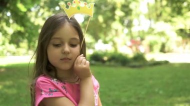 4k. Mutlu kız çocuk kağıt taç ile oynamak, şehir parkı. Prenses gibi portre