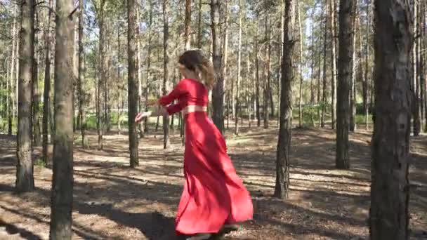 Improvizace moderního tanečníka. Žena zručnost v červených šatech tančí v lesní krajině. 