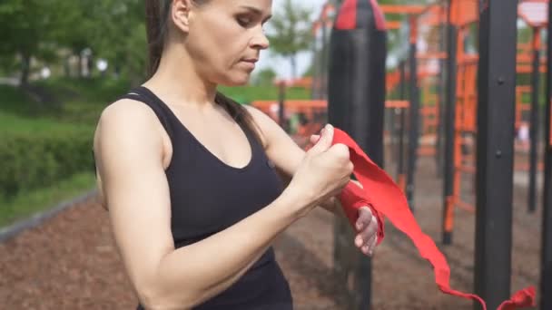 成年女子拳击手在街头训练场准备训练过程 卷起红色磁带 接近场景 — 图库视频影像