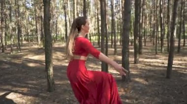 Dansçı doğaçlama. Orman manzarasında dans eden kırmızı elbiseli beceri balerin kadın. Yavaş çekim