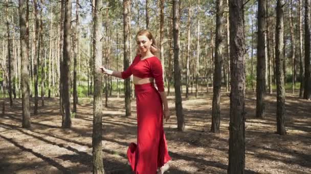 Ballerine contemporaine habillée en robe rouge dansant en forêt. Beauté de l'improvisation de ballet 