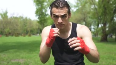 4. gölge ile adam Boxer eğitim. Kamerada darbeler. Şehir Parkı açık spor takımı
