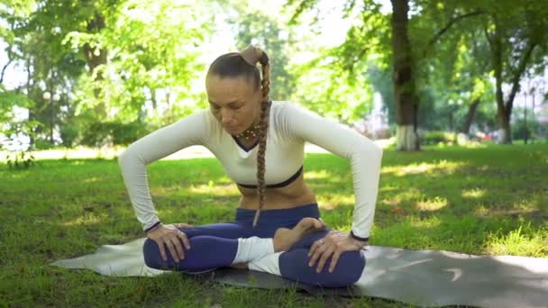 erwachsene Frau im Sommerpark macht Yoga-Meditationsübungen mit Bauch. Zeitlupe
