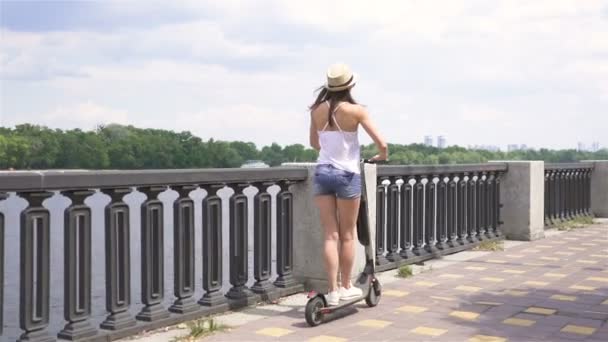 4K市街地で電動スクーターに乗る現代の女の子 安定したショット バックビュー — ストック動画
