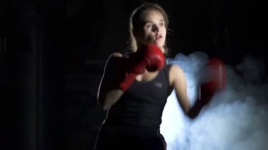 Boks takımı kavramı. Aktif kadın boksör gölgede darbeler yok, karanlık eğitim salonu. 