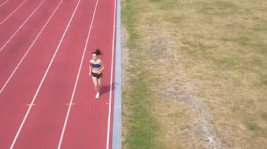 4k Hava. Stadyumda koşan kadının üzerinden arkadan uçun. Sağlıklı yaşam sembolü