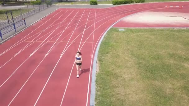 4K空中 スタジアムで走っている女性の上を飛ぶ 健康的な生活 — ストック動画