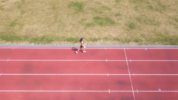 4K空中 スタジアムで走っている女性の上を横に飛ぶ 健康的な生活のシンボル — ストック動画