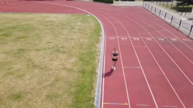 4k . Hava. Genç kadın esmer stadyumda çalıştırmak, üst görünümü. Sağlıklı yaşam, arka sinek 