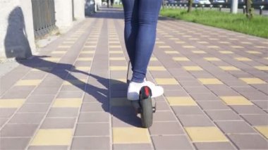 4k. Şehir bölgesinde elektrikli scooter sürme kız kot bacaklar . Sabit atış