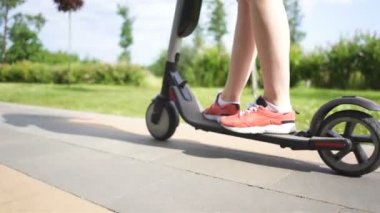 4 k. Şehir parkı alanında elektrikli scooter sürme kız ince bacaklar. Sabit atış
