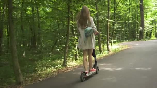 慢动作 年轻性感的女孩骑电动车在城市公园区 背景色 — 图库视频影像