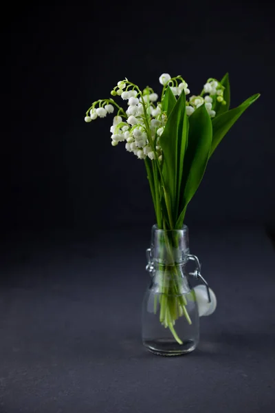 テキストのための場所と黒の背景に谷のユリの花束 繊細な白い春の花 ガラス瓶の中の花束 静物画だ コピースペース — ストック写真