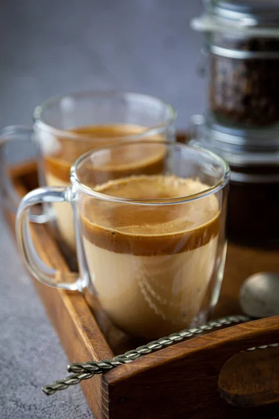 Two transparent cups with double walls. Latte - coffee with milk on a tray. Breakfast is on the table. Still life coffee. Close-up.