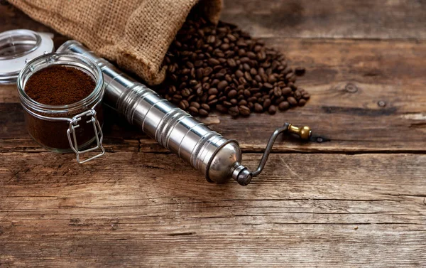 Bag of coffee on a wooden table. Coffee beans and ground in a jar. Manual coffee grinder. Top view, place for text. Brown background. Packing coffee in a pack. Cup with a drink.