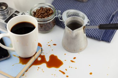 Masaüstündeki bir kitaba kahve döküldü. Kahve, kahve çekirdekleri, beyaz bir fincan kahve, masaya bir içki dök, su birikintisi yap ve kitabı mahvet..