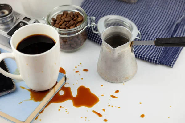 Masaüstündeki bir kitaba kahve döküldü. Kahve, kahve çekirdekleri, beyaz bir fincan kahve, masaya bir içki dök, su birikintisi yap ve kitabı mahvet..