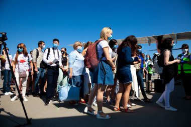 Kyiv, Ukrayna - 27 Haziran 2020: Yolcular uçağa biniyor. Maskeli insanlar uçağa biner. Boryspil Havaalanı, Windrose Havayolları uçağı. Pist. Karantina ve koronavirüs boyunca seyahat edin..