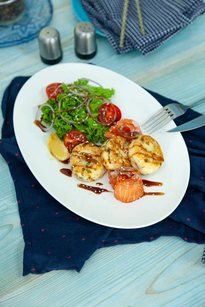 Fish cakes with salad, tomatoes and red onions in a restaurant on a white plate. Red salmon fish. Fish menu. Close-up. Healthy Omega-3 food. — Stock Image Fish Cakes Salad Tomatoes Red Onions Restaurant White Plate Red Royalty Free Stock Photos