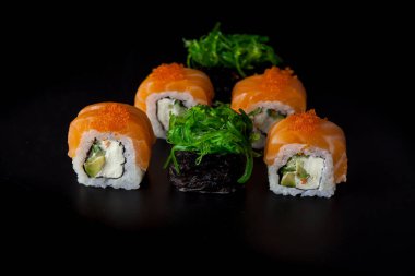 Somon suşi seti. Suşi Philadelphia 'yı kırmızı balıklı, somonlu, kırmızı havyarlı. Masaj havyarının altında yumuşak avokado ve krem peynirle yuvarlan. Siyah arka planda klasik suşi..
