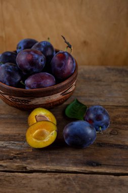 Ahşap bir masada kasede mavi erik. Kesik erik. Üst görünüm, metin için yer. Fotokopi alanı olan meyve arkaplanı. Durgun yaşam yemeği.