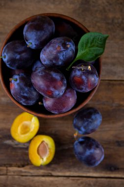Ahşap bir masada kasede mavi erik. Kesik erik. Üst görünüm, metin için yer. Fotokopi alanı olan meyve arkaplanı. Durgun yaşam yemeği.