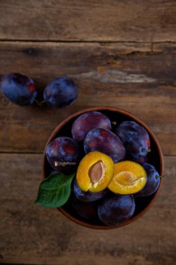 Ahşap bir masada kasede mavi erik. Kesik erik. Üst görünüm, metin için yer. Fotokopi alanı olan meyve arkaplanı. Durgun yaşam yemeği.