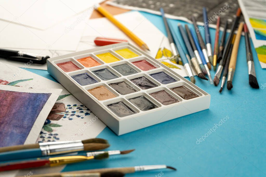 Watercolor paints and brushes. Artist's workplace and desk. Color palette. Drawing background. Place for your text.
