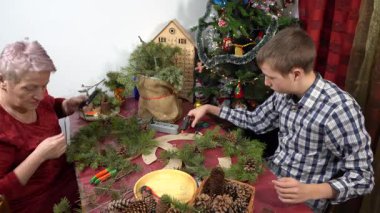 Büyükannem ve torunum birlikte Noel çelengi yapıyorlar. Yaşlı kadın ve genç çocuk dekore ediyor. Aile Zirvesi