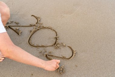 El, kuma rakamlar yazar. İki sıfır 202... yıl. Kumsal denizi