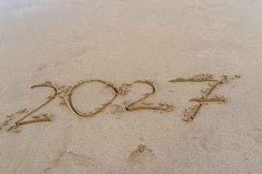 2027 numara kumsalda yazılmış. Deniz arkaplanı.