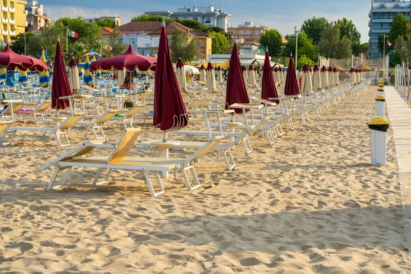 Kumlu bir sahilde güneşleniyorlar. Şemsiye ve sandalyeler. Boş sahil beldesi İtalya. Sahil şeridi şezlongunda güneşlen.