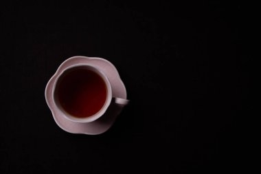 Siyah arka planda seramik çay fincanı. Siyah çay ile pembe bardak.