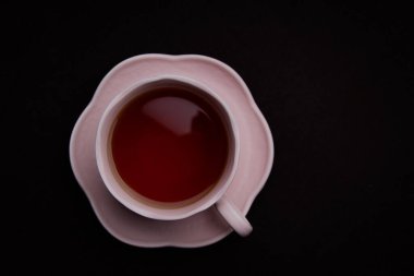 Siyah arka planda seramik çay fincanı. Siyah çay ile pembe bardak.