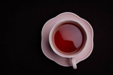 Siyah arka planda seramik çay fincanı. Siyah çay ile pembe bardak.