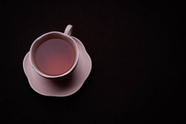 Siyah arka planda seramik çay fincanı. Siyah çay ile pembe bardak.