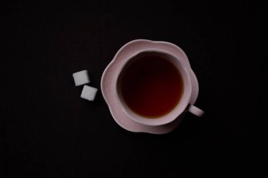 Siyah arka planda seramik çay fincanı. Siyah çay ile pembe bardak.