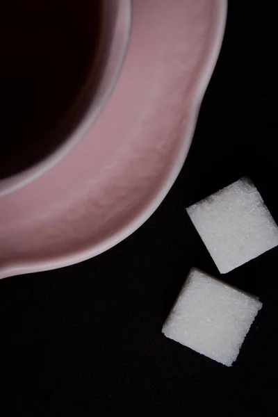 Siyah arka planda seramik çay fincanı. Siyah çay ile pembe bardak.
