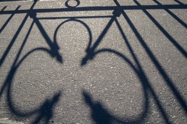 Üzerinde, köprünün kafesinin gölgesini yansıtan asfalt fotoğrafı.