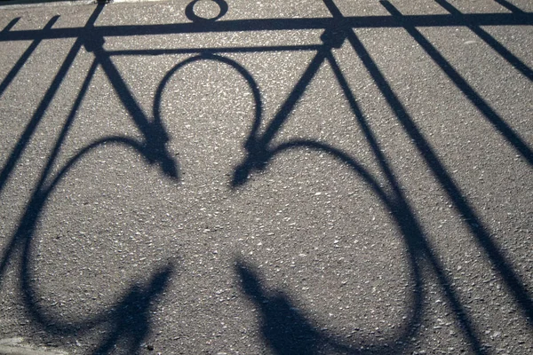 Üzerinde, köprünün kafesinin gölgesini yansıtan asfalt fotoğrafı.