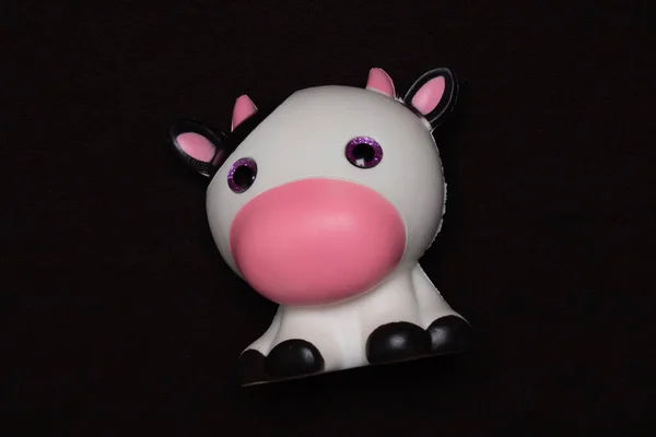 Soft toy cute cow on a dark background. Plastic toy