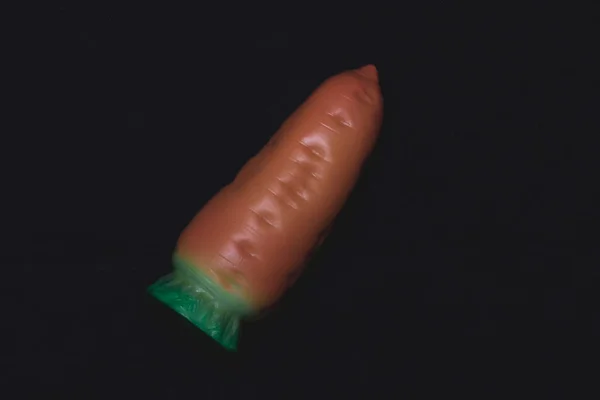 Siyah arka planda oyuncak havuç. Plastik oyuncak.