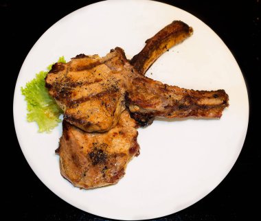 Kemik ve beyaz plaka üzerinde domuz eti biftek