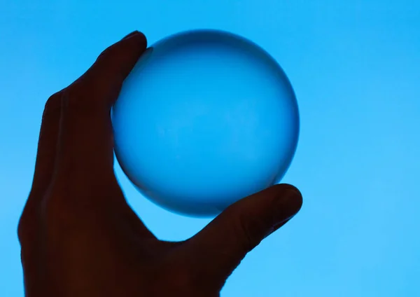 Mano Sosteniendo Una Bola Cristal Con Fondo Azul —  Fotos de Stock