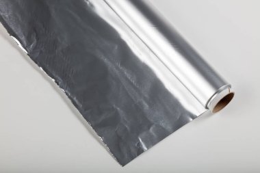 Beyaz zemin üzerine alüminyum folyo rulo yakın çekim.