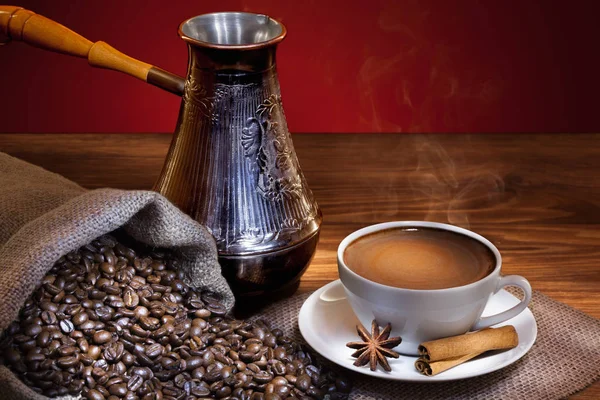木桌上的一杯热咖啡 配烤豆和土耳其咖啡壶 — 图库照片