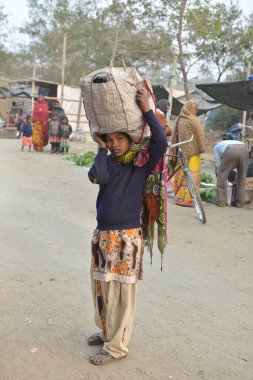  GAYA, BIHAR, INDIA - 25 Şubat 2019: büyük çantasını kafasında taşıyan yerel kız