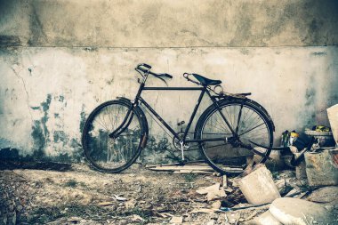 Beton duvarın yanına park edilmiş eski bir bisiklet..