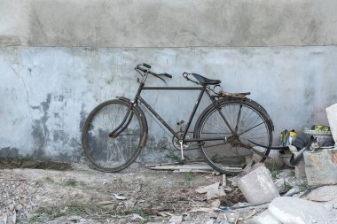Beton duvarın yanına park edilmiş eski bir bisiklet..