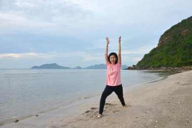 sağlıklı bir kadın gün doğumunda plajda yoga yapıyor.